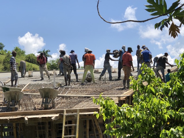 Buckets of concrete being passed by hand across the roof.