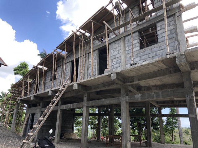 Plywood and 2 x 4’s held up by bamboo poles on the overhang of the new roof.