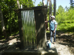 Wilton examining a latrine that was repaired through our Earthquake Relief Program